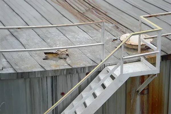 dented and corroded metal jacket insulation allows water leakage on storage tank roof