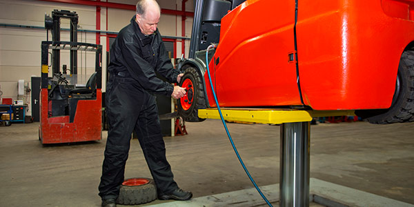 mechanic replaces damaged forklift tire