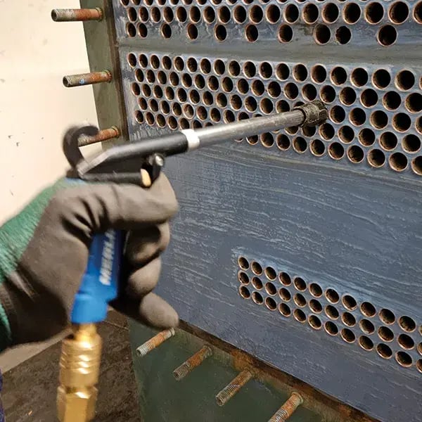 compressed air id directed into heat exchanger tubes to blow out residual dust and debris after coating work