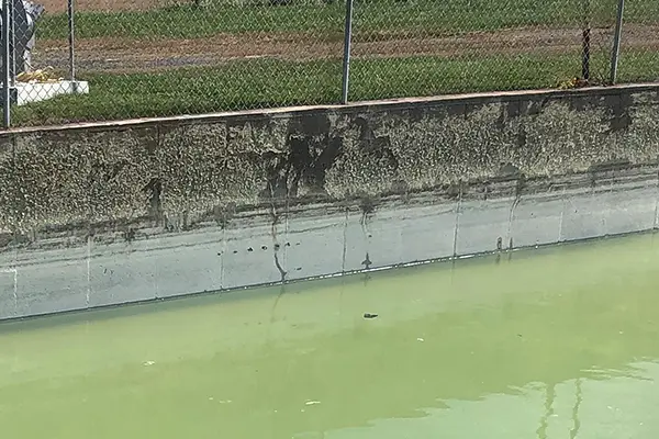 concrete tank wall with failed coating and spalled concrete damage