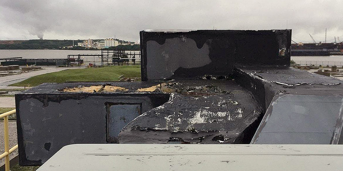 Rusted sheet metal air duct underneath wet, deteriorated insulation on a building rooftop