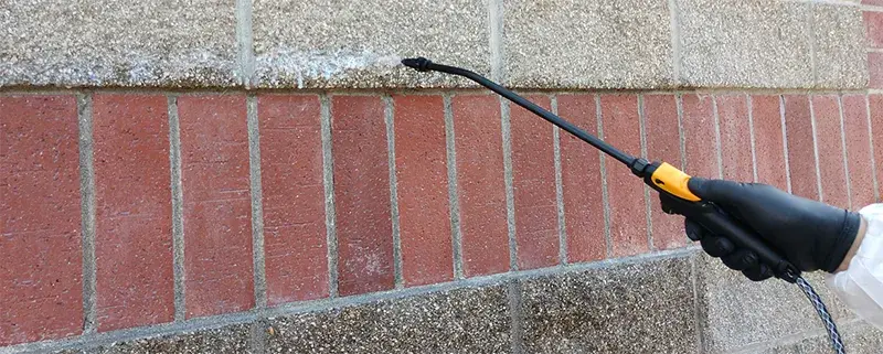 watreproof coating is sprayed onto a brick building wall