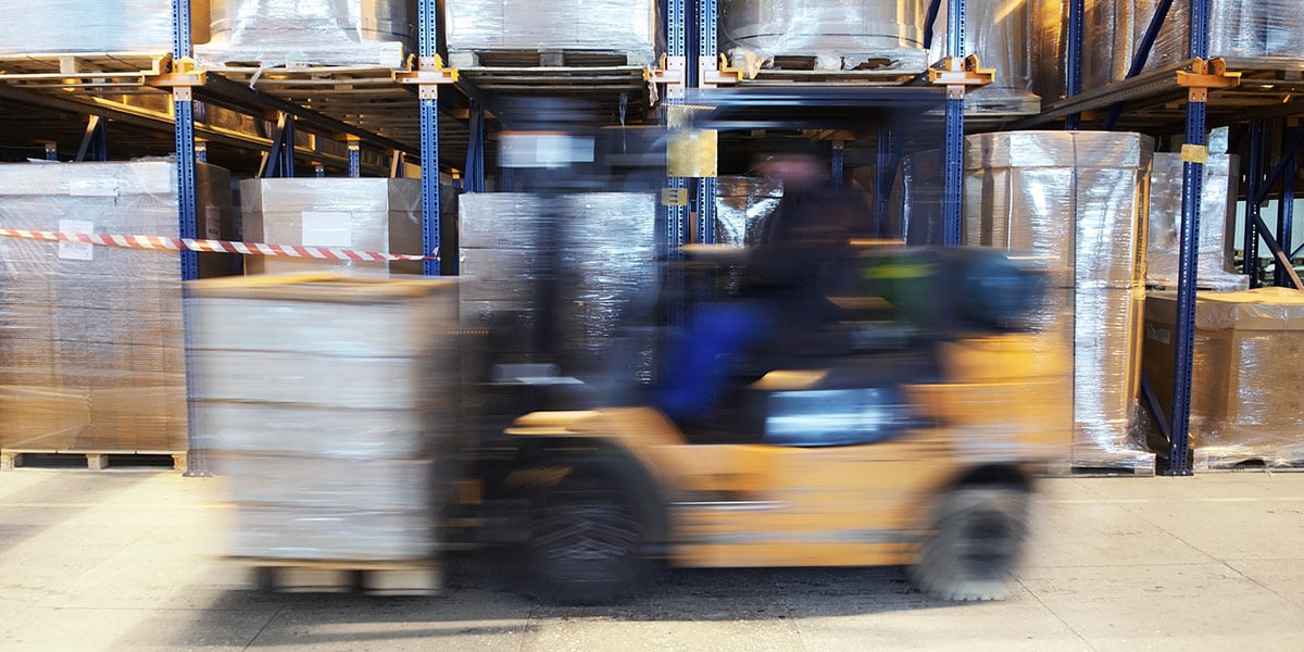 Forklift moving across concrete floor in warehouse