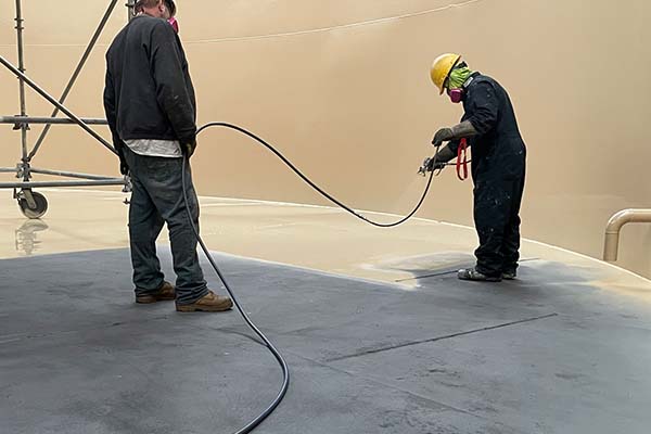 spray application of protective coating to interior tank floor