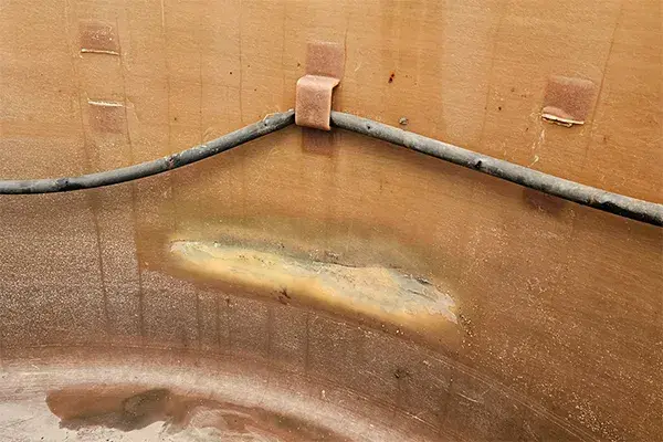fiberglass storage tank with internal damage and broken support brackets